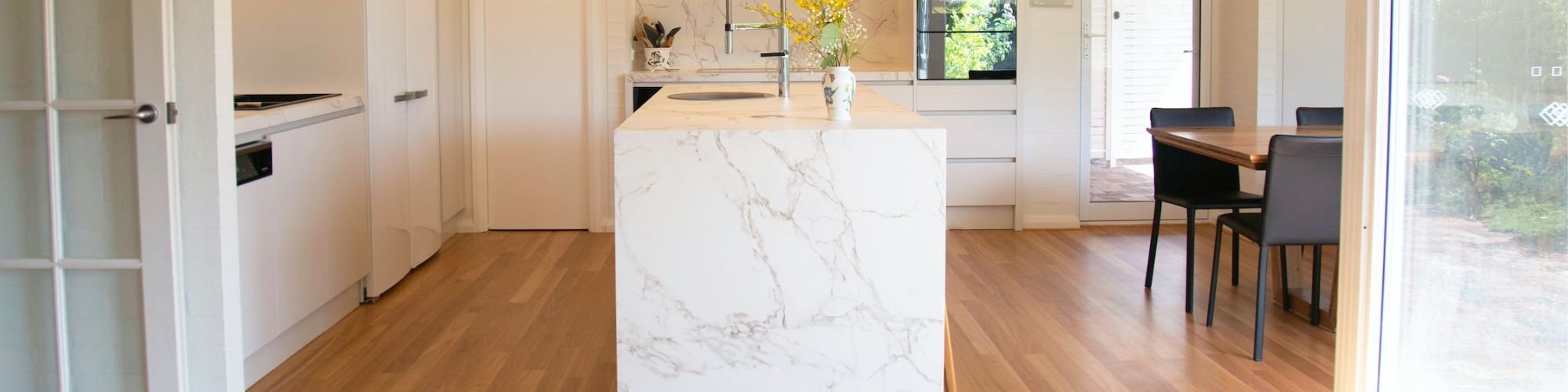 Brown wood-look floors in a bright kitchen with white marble countertop.