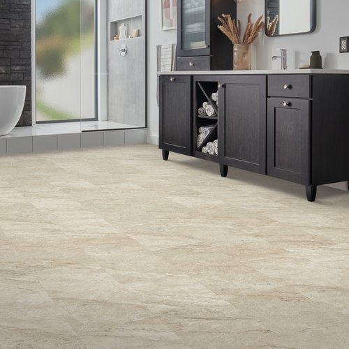 Stone-look luxury vinyl tile (LVT) flooring in a modern bathroom with a freestanding tub and dark wood vanity.