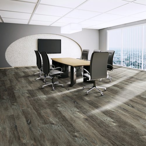 Modern office space featuring dark wood-look luxury vinyl tile (LVT) flooring with a conference table and rolling chairs, highlighting durable and professional-grade commercial flooring.